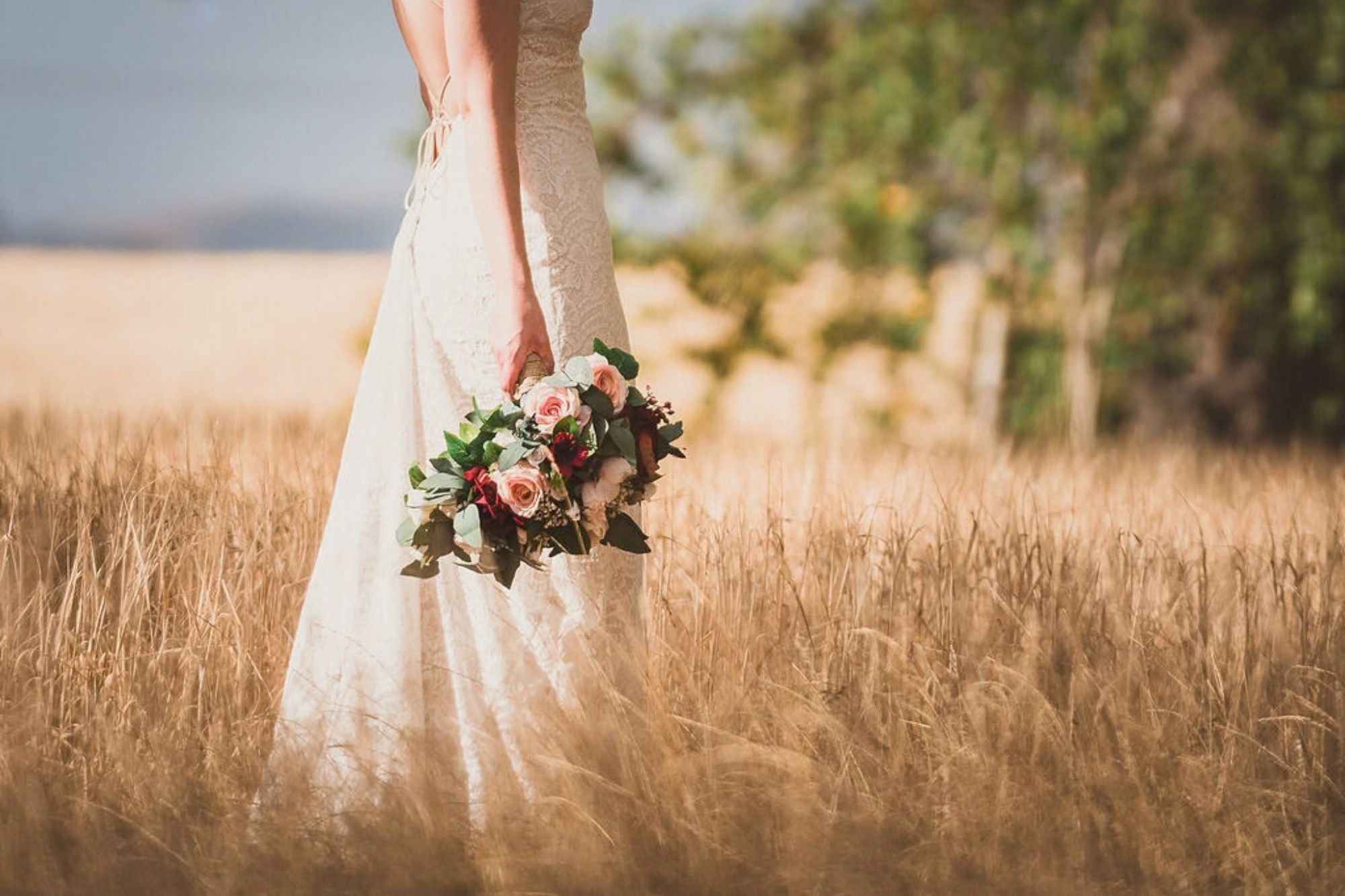 flowergirl bridal bouquet held by bride in long grass